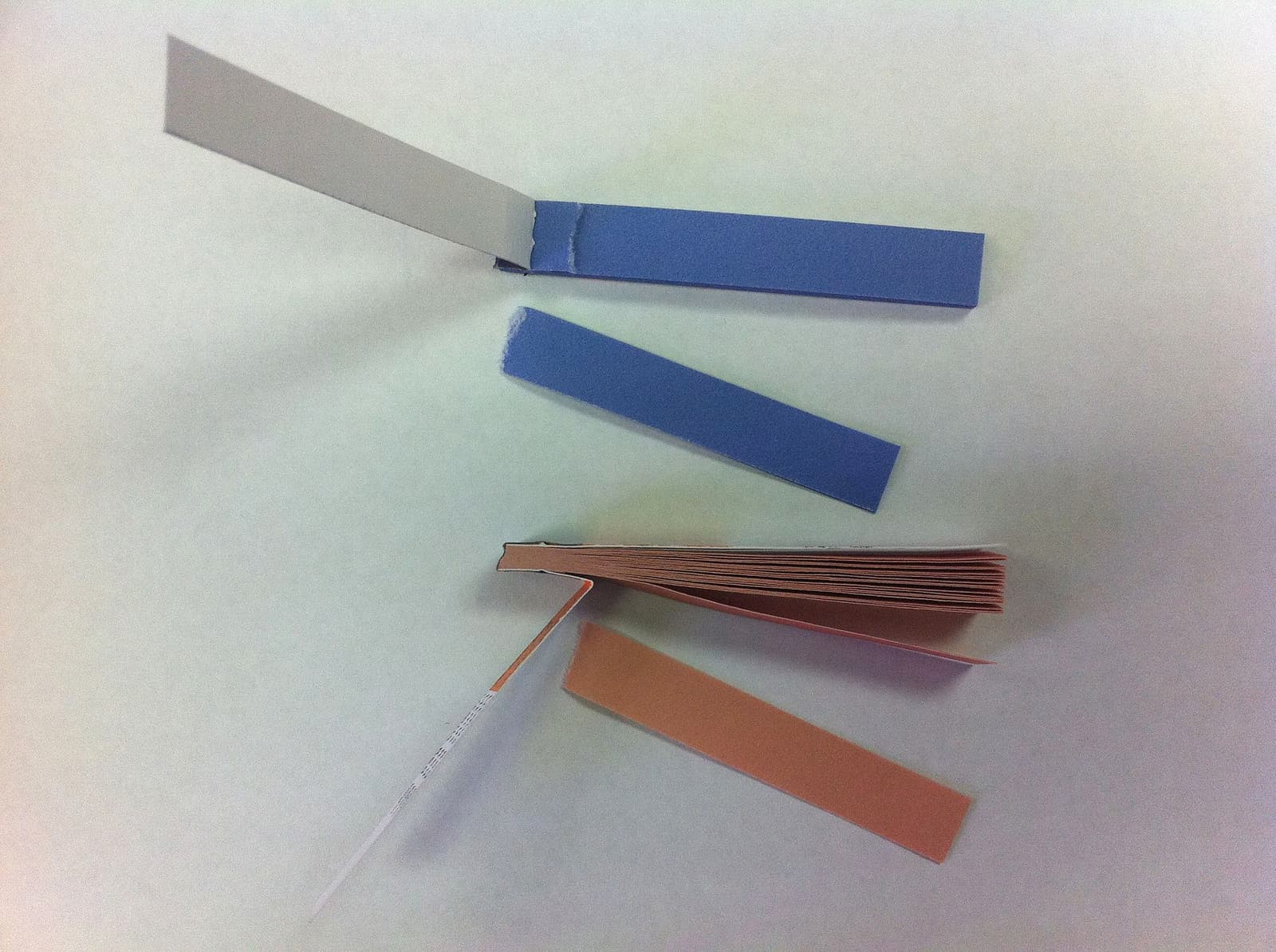 Strips of blue and red litmus paper laid out for comparison - the simplest acid-base indicator and the visual archetype for hobby pH test strips.